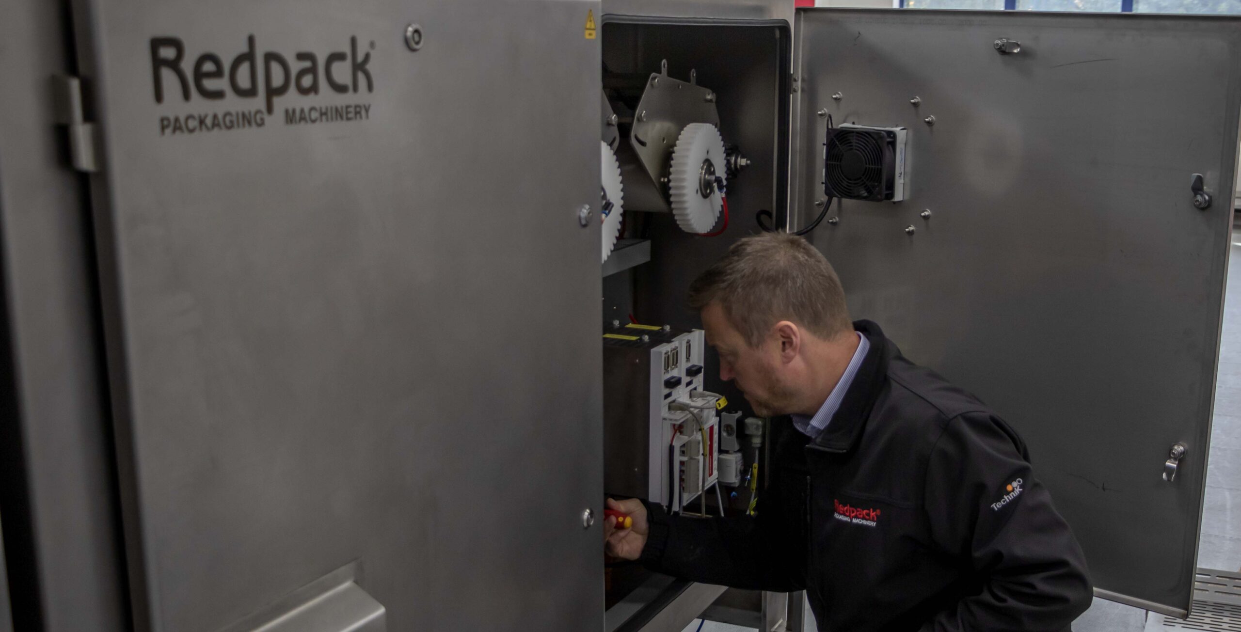 Technical Service from redpack Packaging Service Flow Wrapping Machinery Ein Techniker wartet eine Redpack-Verpackungsmaschine